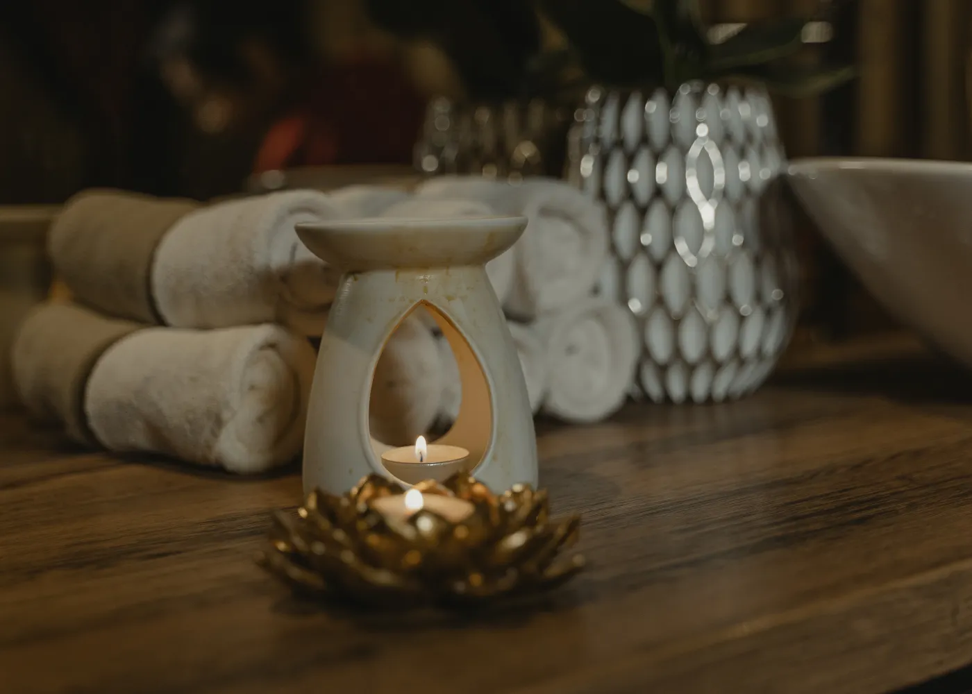 Candle, rolled towels and plant on a wooden table