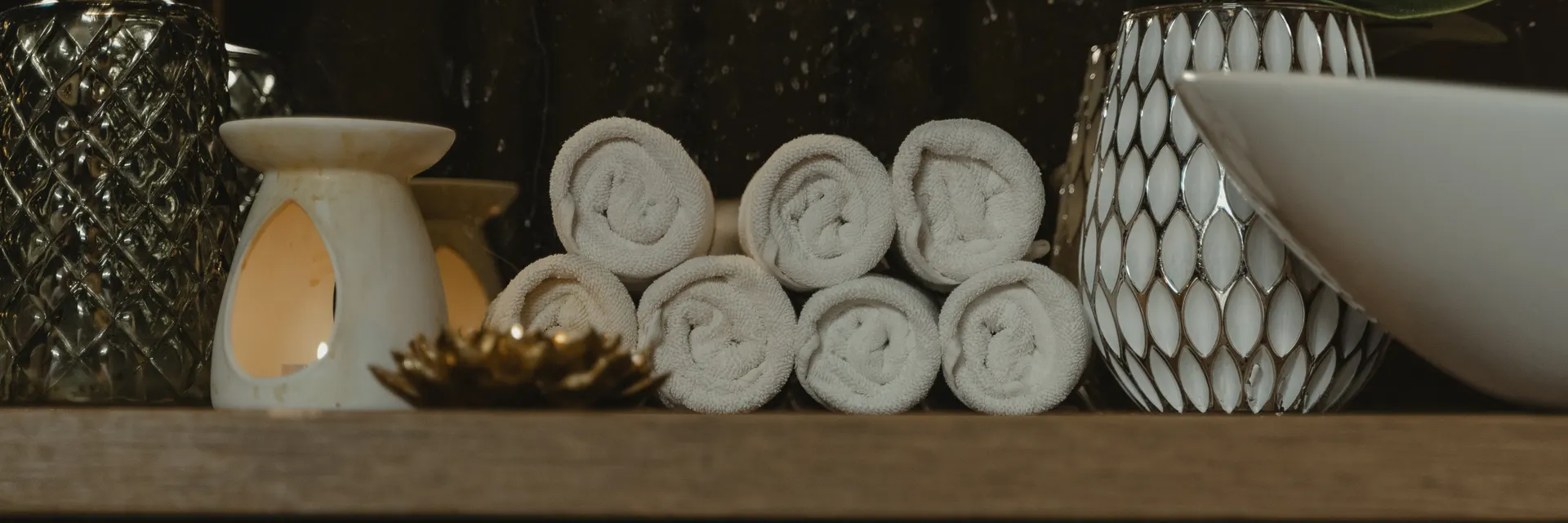 Rolled towels and an aromatherapy candle on a shelf