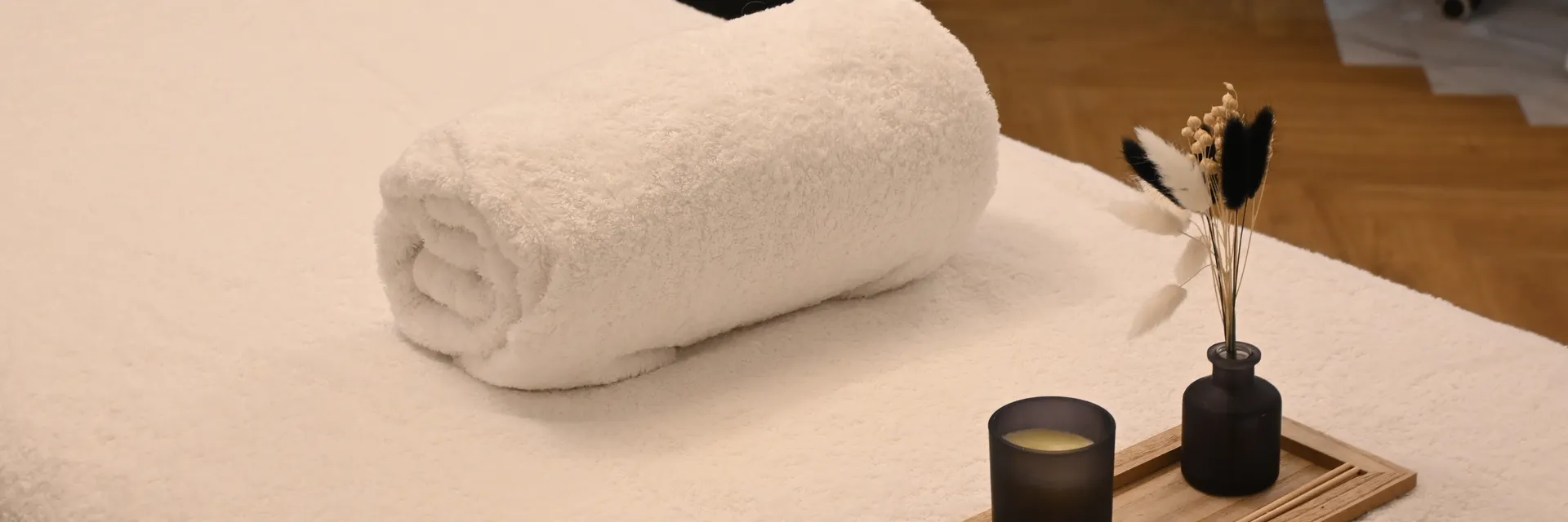 Rolled towel and candle on a massage table
